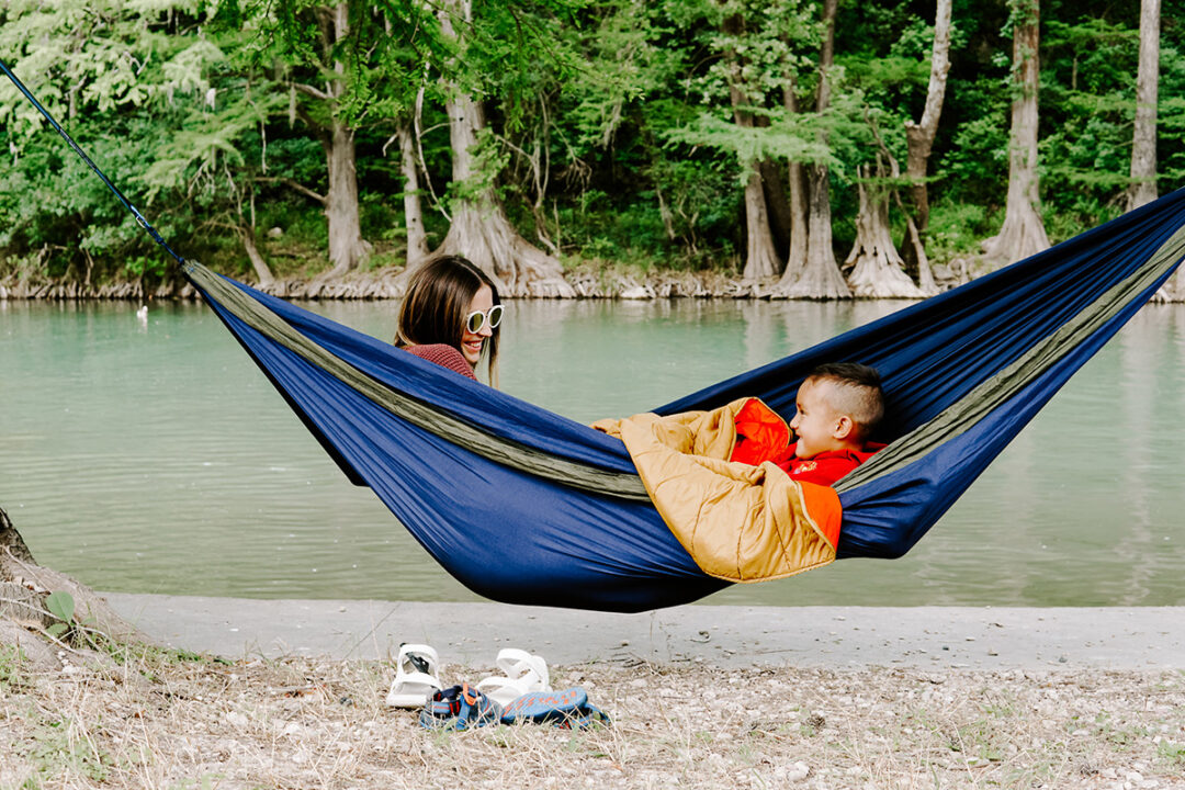 Mom and son in DoubleNest hammock outside by lake.