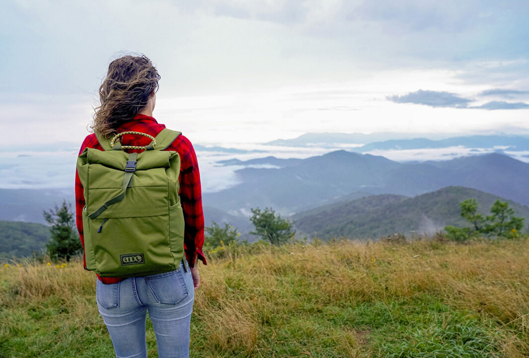 Woman on top of mountain using Roan Rolltop Pack.