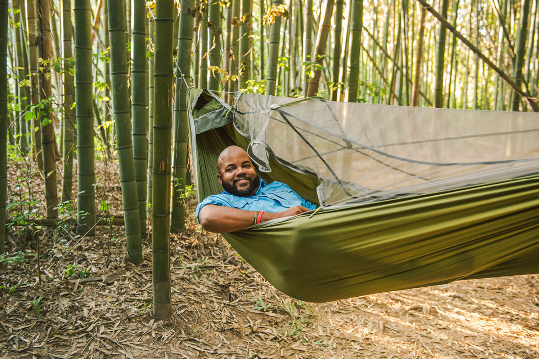 Man laying in green JungleNest hammock in a bamboo forest.