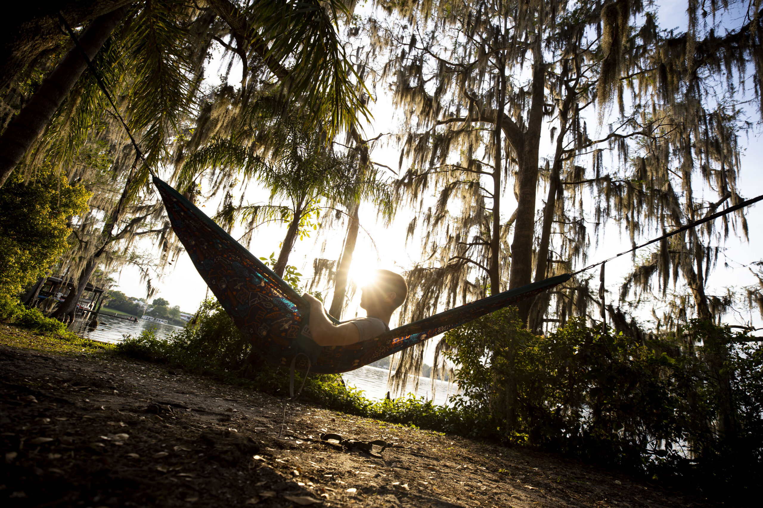 A man lays in a hammock surrounded by Spanish Moss in Azalea Garden in Winter Park, Florida.