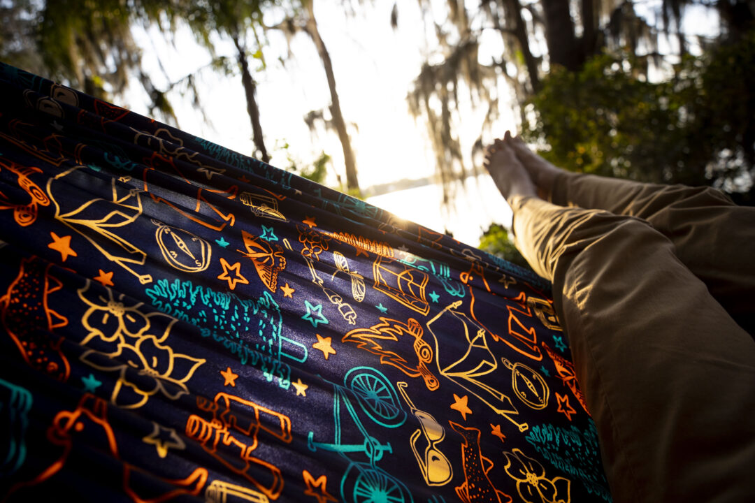 A man lays in a hammock surrounded by Spanish Moss in Azalea Garden in Winter Park, Florida.